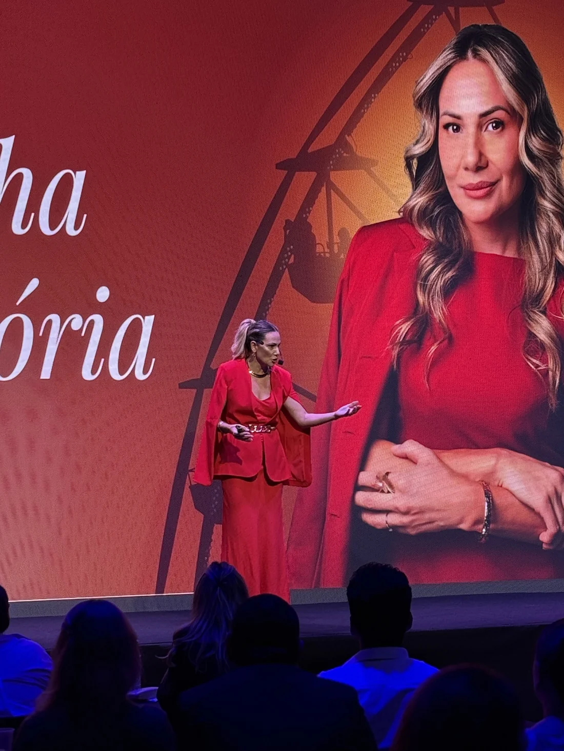 Fabíola Luz conduzindo um encontro em um palco com telão